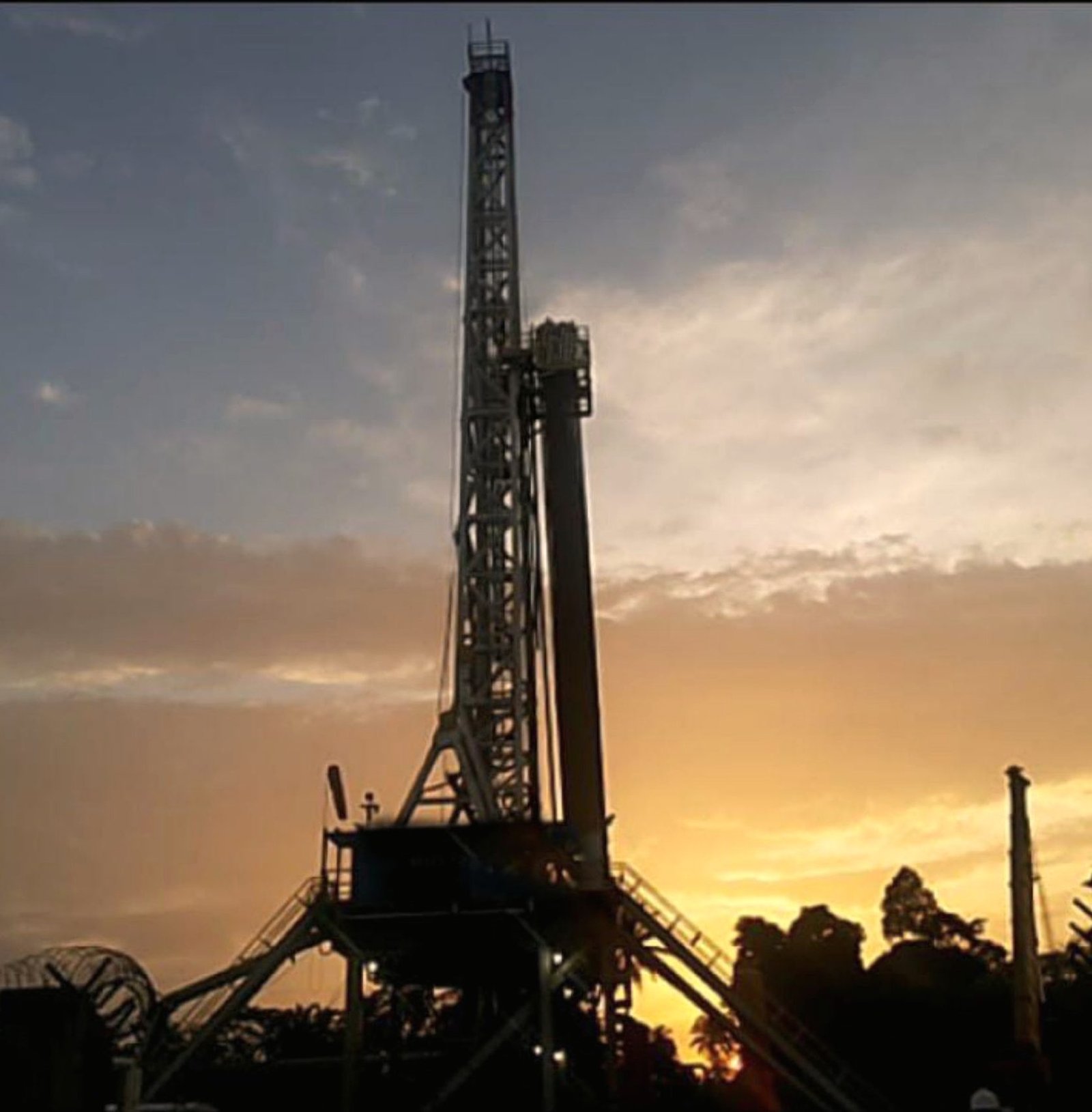 Silhouette of a land drilling rig against a sunset sky