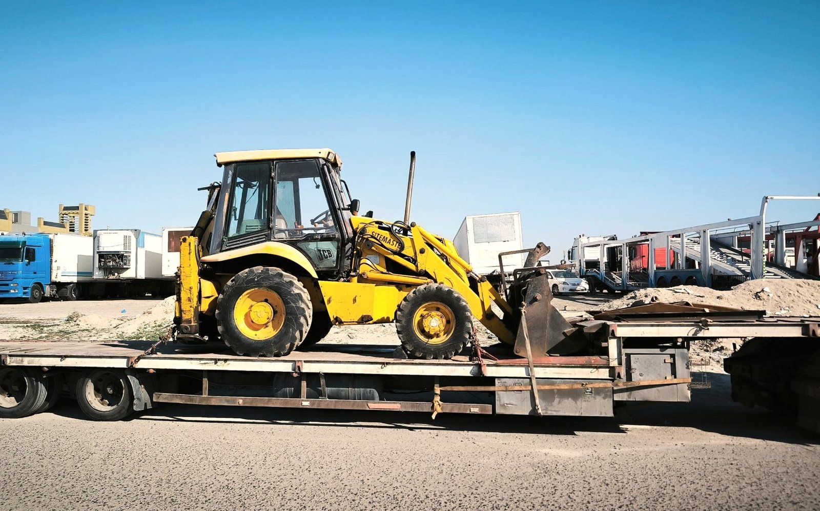 Backhoe loader chained down on a flatbed trailer