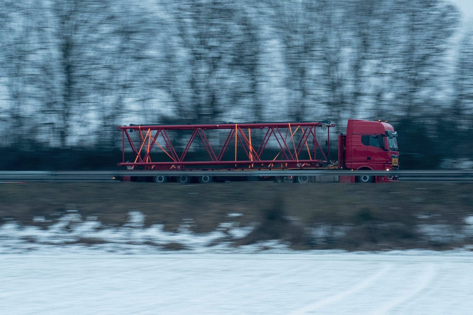 Truck carrying a long steel structure down a winter highway