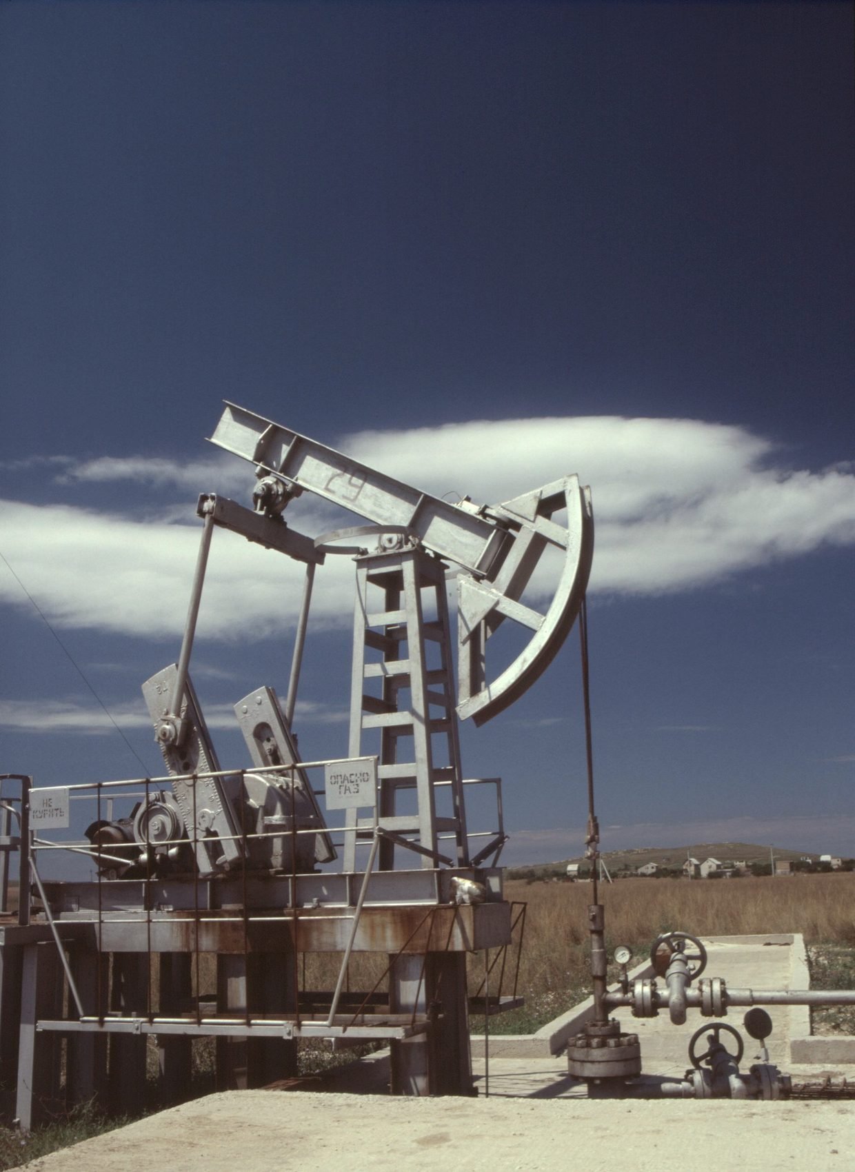 Pump jack working against a tall cloud and open sky
