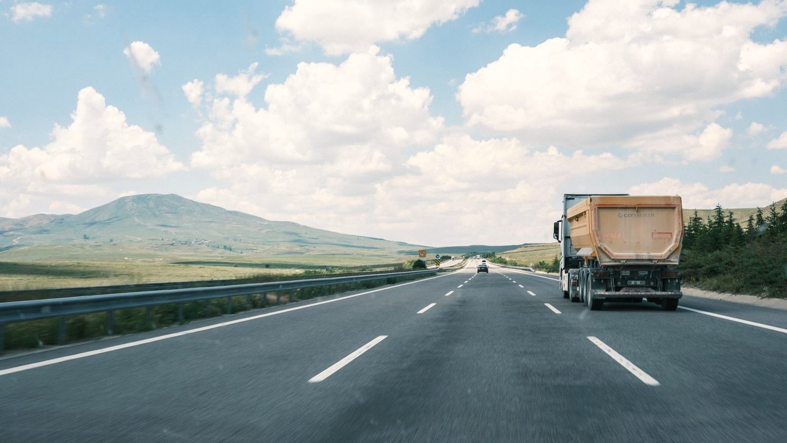Truck on a highway with a flat-topped butte in the distance