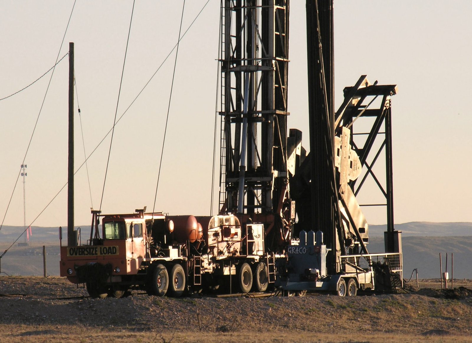 Mobile drilling rig and a service truck set up on open Wyoming ground